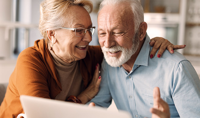 Happy mature couple using laptop at home