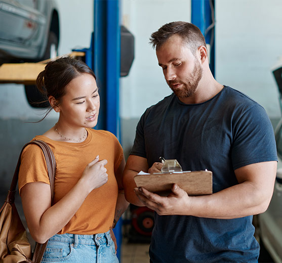 Woman talking to male mechanic about auto repairs.