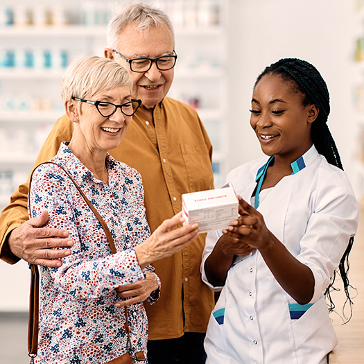 Pharmacist advising senior couple in choosing vitamins in drugstore.