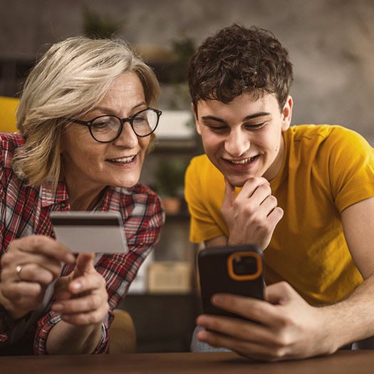 Mother and her teenage son shopping online using mobile phone and debit card 