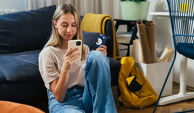 Teen checking her phone with her debit card