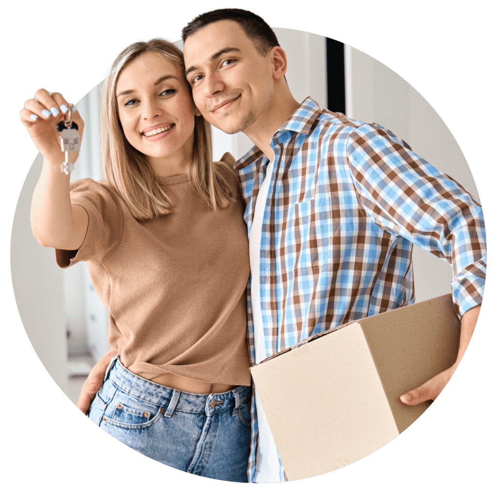 Young couple holding keys to new home and moving box