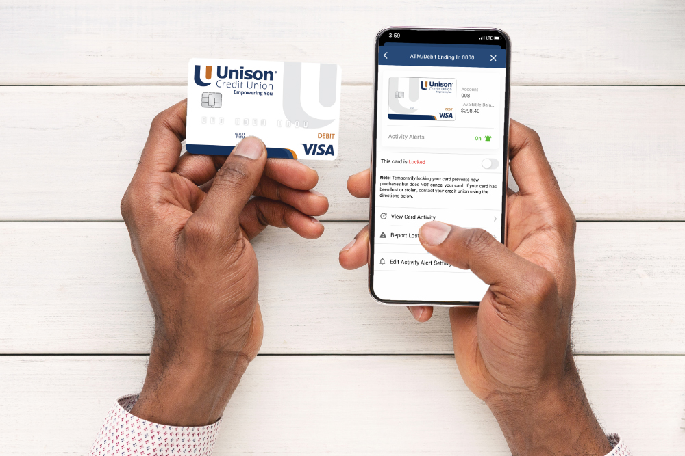 5 Best Practices To Protect Yourself From Fraud - Man holding his Unison Debit Card and turning reporting fraud on mobile app