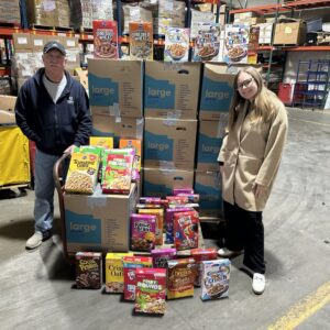 Two employees standing next to 350 cereal boxes.